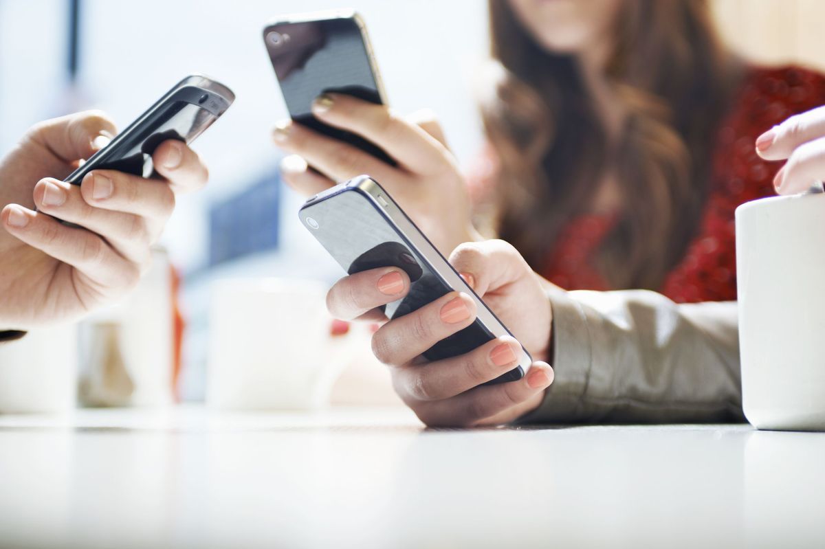 mãos enviando mensagens de texto com telefones celulares em um café
